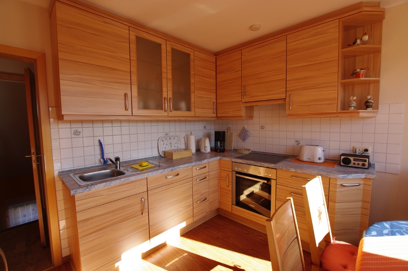 Helle Holzküche mit Backofen, Ceranfeld und Sitzplatz am Fenster