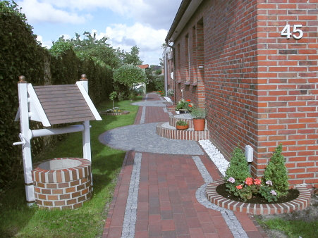 Eingangsbereich der Ferienwohnung mit gepflastertem Weg und Ziehbrunnen