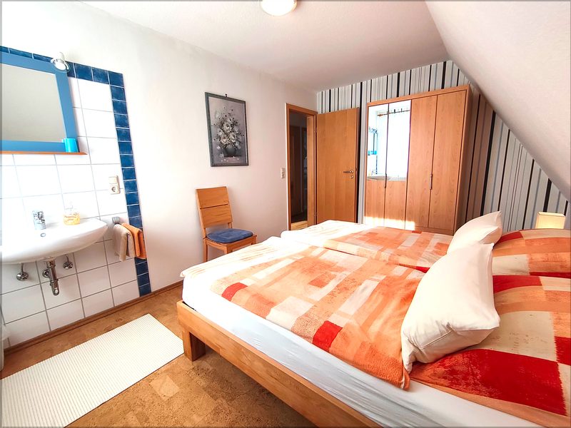 Helles Schlafzimmer mit Doppelbett, Kleiderschrank und separatem Waschbecken
