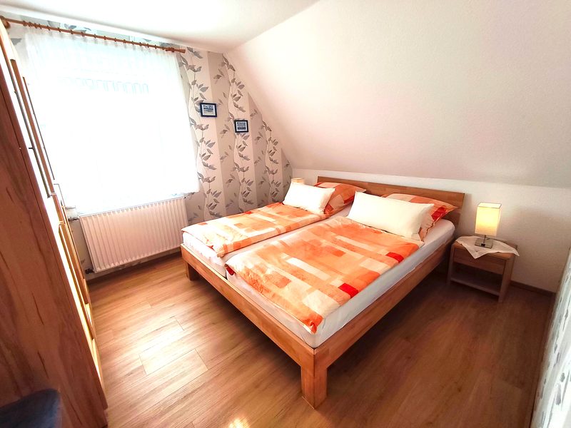 Schlafzimmer unter der Dachschräge mit Doppelbett, Nachttisch und Kleiderschrank
